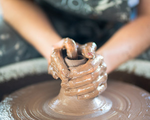 Woman making ceramic pottery on wheel, hands close-up, creation of ceramic ware. Handwork, craft,...