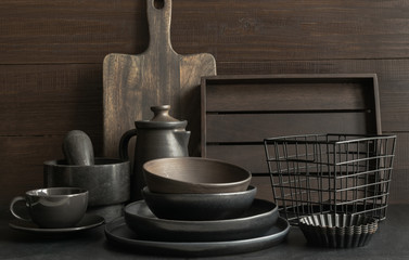 Crockery, clayware, dark utensils and stuff on dark tabletop. Kitchen still life.