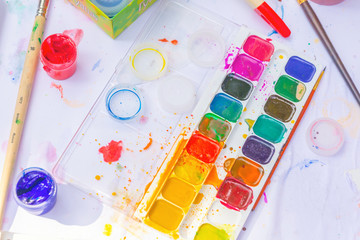 A set of acrylic paints, gouache and brushes on a white sheet, Text in Russian: gouache