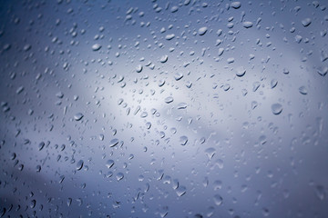 Drops of rain on glass , rain drops on clear window. Water condensation on transparent glass over gray or blue sky - 250647817