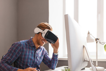 Smiling man in VR goggles working in office