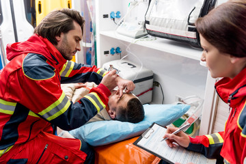 Paramedic doing eye examining in ambulance car