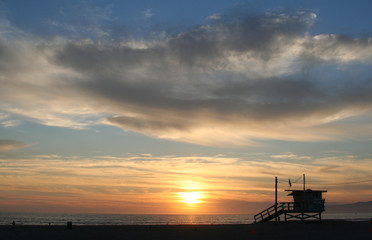 Silouetted lifeguard station against a dramatic sunset sky