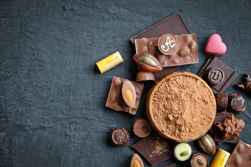 Assorted chocolate and cocoa powder on black background