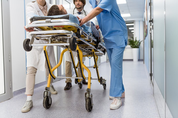 Cropped view of doctors and nurse transporting unconscious patient - Powered by Adobe
