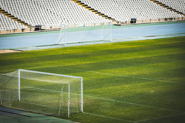 Fototapeta premium Empty European European football stadium. soccer field with grass and grandstand on a sunny day