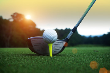 golf club and golf ball close up in grass field with sunset. Golf ball close up in golf coures at...