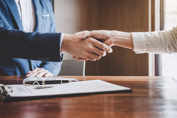 Real estate agent and customers shaking hands together celebrating finished contract after about...