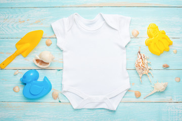 Mockup Flat Lay white baby bodysuit shirt on a blue rustic wood background with a nautical...