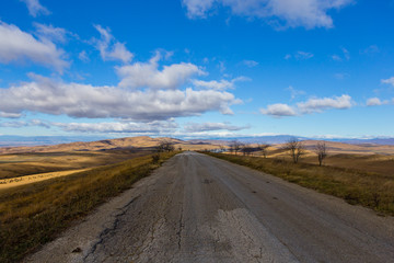 Fototapeta na wymiar one old road in the field, clouds, landscape, sunny weather, Georgia, asphalt, summer