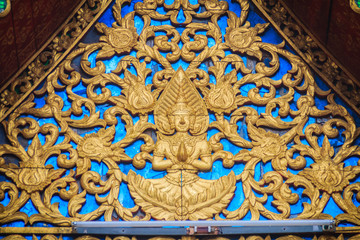 Beautiful golden gable chapel with engraved angel sculpture. An angel sculpture was decorated on the gable top at the temple in Thailand.