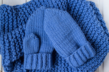 Fototapeta na wymiar Knitted blue scarf and mittens. Woolen clothes