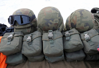Part of military equipment – helmets, first-aid kits, carpets – placed on a table