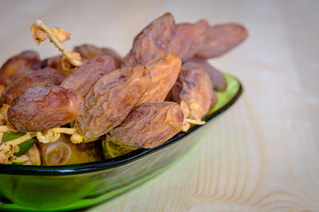 Dried dates on a green bowl.