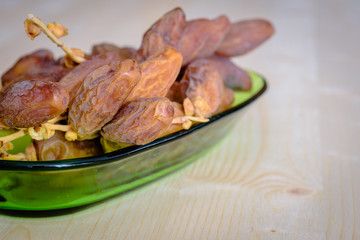 Dried dates on a green bowl.