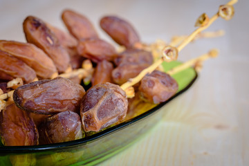 Dried dates on a green bowl.