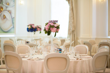 Interior. round table and chair with white table cloth combined by flower bouquet on tall