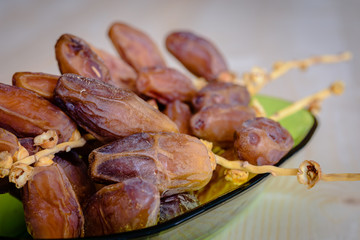 Dried dates on a green bowl.