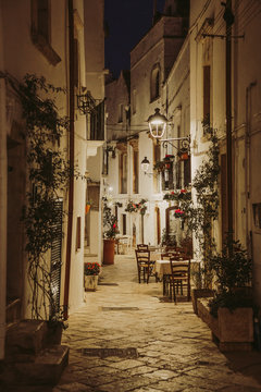 Fototapeta Narrow white street and restaurant tables in Locorotondo, region Puglia, Italy