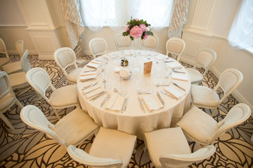 Interior. round table and chair with white table cloth combined by flower bouquet on tall