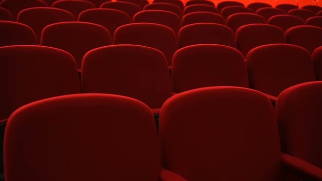 Rows of empty red velvet seats inside a theater or opera
