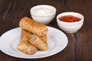 Pancake rolls with meat filling, served with sour cream and ketchup sauce