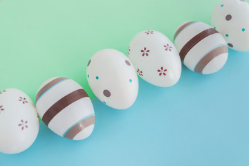 Eggs decorated with stripes and flowers on green and blue background, Easter concept.