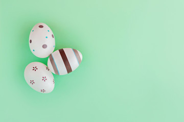 Eggs decorated with stripes and flowers on green background, Easter concept.