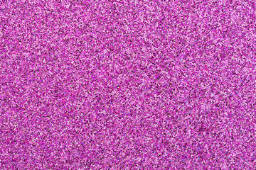 Close up on a pink glitter festive background. Sheet of pink and purple confetti. Macro.