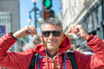 Man happy for New Orleans Mardi Gras, holding beads and smiling
