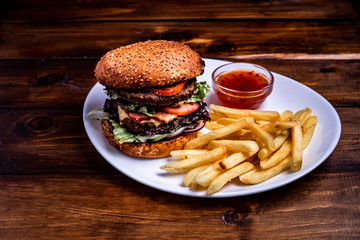 Close-up on a wooden board beef burgers, crispy loaf, lettuce, cheese, cucumbers, trendy food