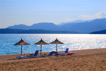  Parasols at the beach in front of the Peloponnesian mountains, Gythio bay, Greece