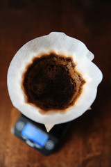 Alternative manual coffee brewing in pink ceramic dripper with paper filter. On electronic scale. Top view close up