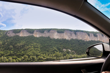 Mountains behind the window of the car.