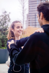 Fototapeta premium Male coach helping young woman exercising at outdoors