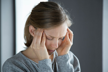 Sick woman at home massaging temples, feeling strong headache