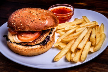 Craft beef burger and french fries on wooden table isolated on black background.