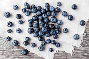 Blueberries lie on homespun tablecloth. Rustic cozy background with healthy food. Fresh-gathered berries full of vitamins, good for diet nutrition and healthy meals.