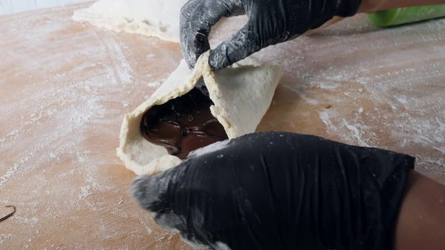 Chef hands work with dough prepares sweet pastries with chokolate