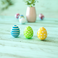 Three colorful Easter eggs on green wood