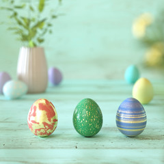 Three colorful Easter eggs on green wood