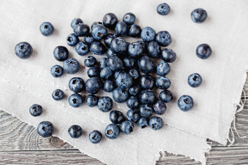 Blueberries lie on homespun tablecloth. Rustic cozy background with healthy food. Fresh-gathered berries full of vitamins, good for diet nutrition and healthy meals.