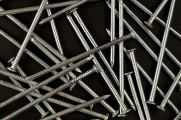 Background. A structure consisting of new shiny nails on a dark background.