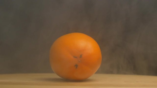 Rotating ripe persimmon from which blows freshness and coolness on a black background, close-up, slow motion, fruits