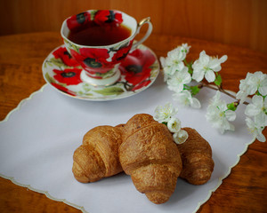 Croissants decorated with spring flowers. A cup of tea. Close-up. Spring.	