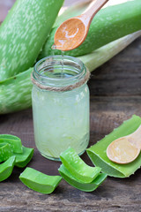 Fresh aloe vera plant, stem slices and gel on wooden background, skin therapy concept