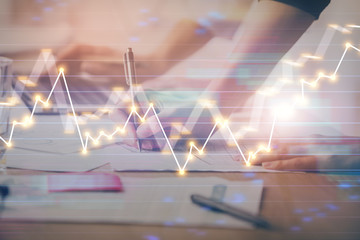 Close up of hands writing with double exposure of business charts. Financial concept.