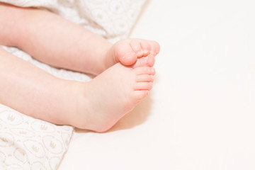 Fototapeta na wymiar Baby feet in the bed. Copy space.