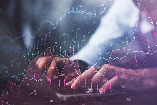 Hands typing on laptop. Business and Financial concept. Double exposure of stock market charts.