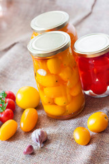 Glass jars with homemade pickled tomatoes, sealed with metal lid
